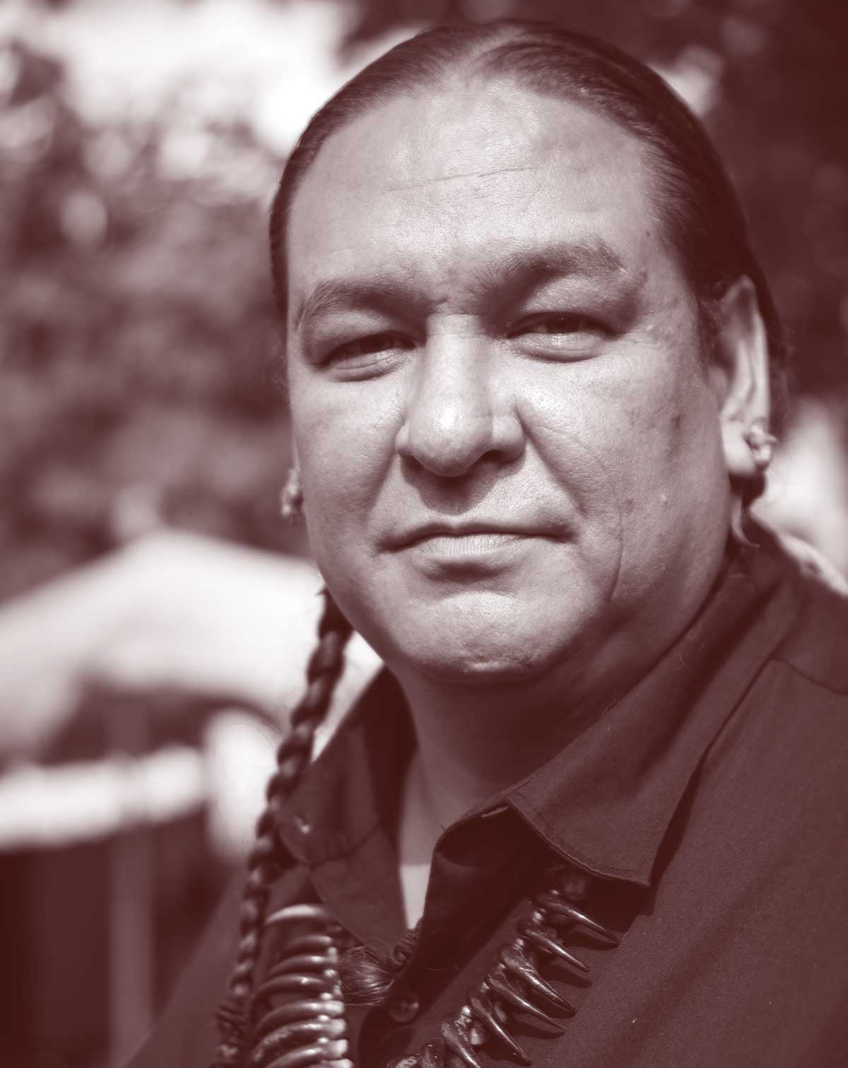 Photo of a man with braided hair and a dark collared shirt