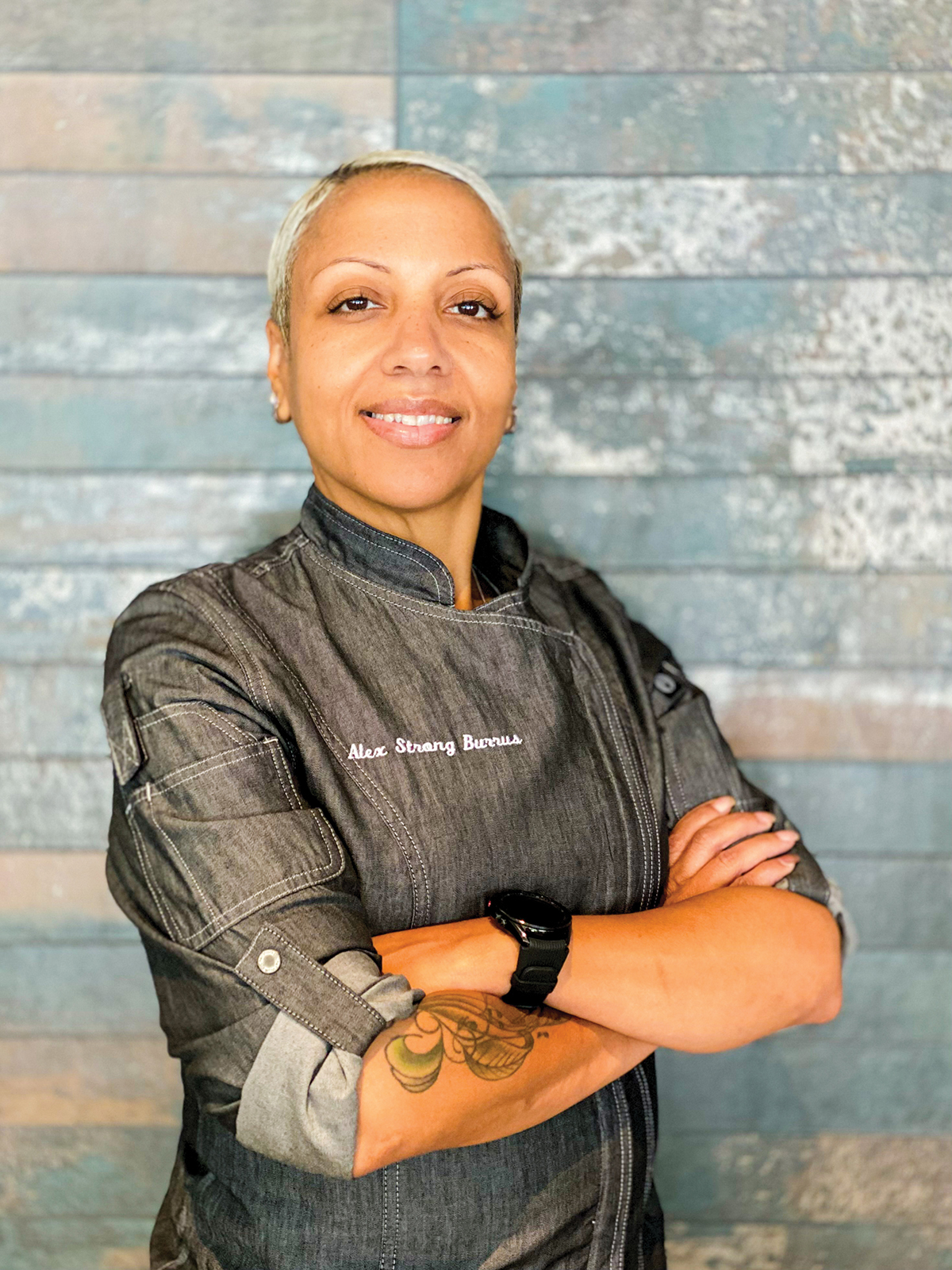 A portrait of a smiling chef with arms crossed in front of her chest