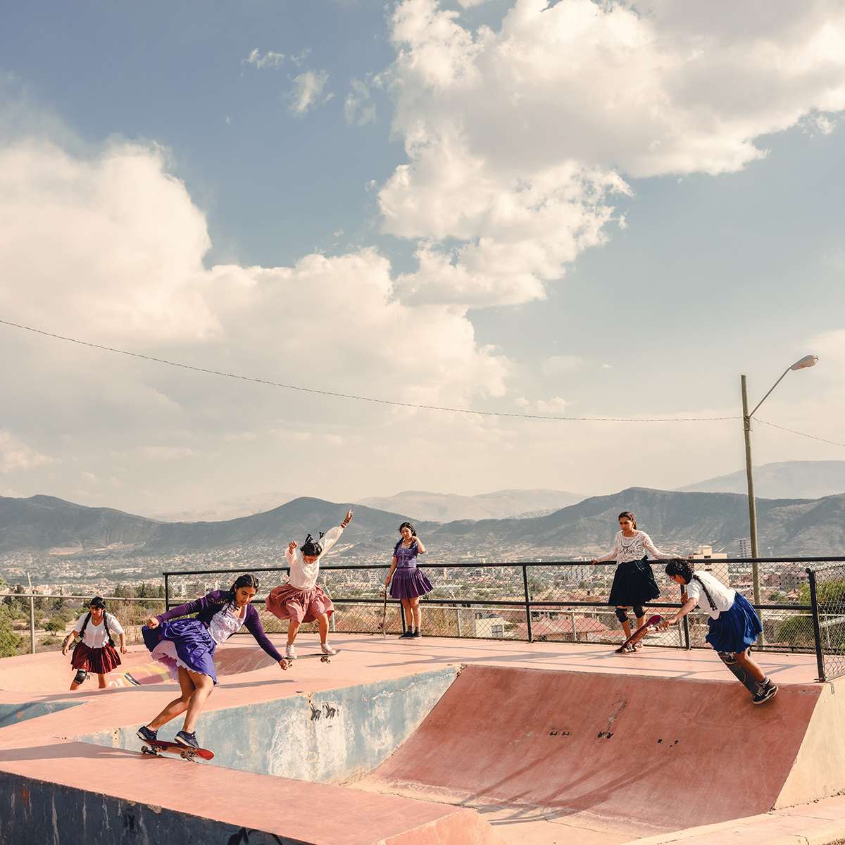 A group of skaters wearing skirts in action at a skatepark