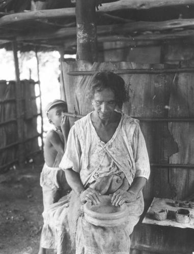 Cypriana Gainsa, a Taino woman from Yara, makes a pot as a child looks on