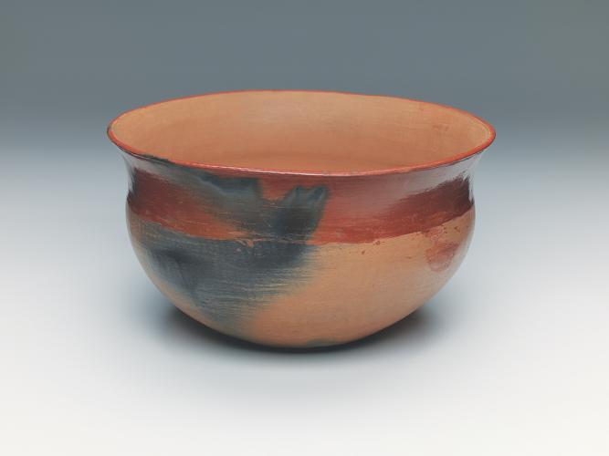 Buff ware bowl with red rim and black designs caused by clouds of smoke