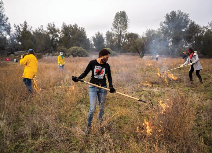 Volunteers raking fire in an attempt to spread flames across a meadow