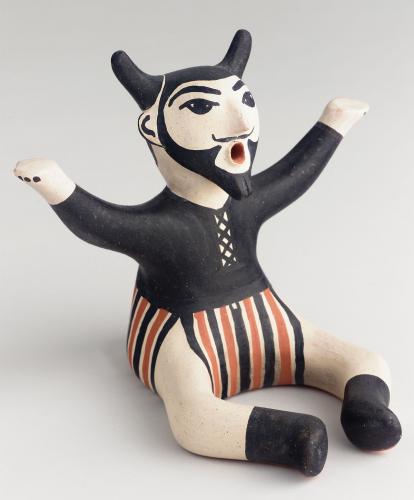 Cochiti seated, bearded rain god figurine with horns, black shirt and striped pants.