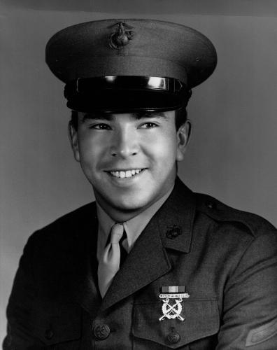 A black and white image of a young Dugan Aguilar in his U.S. Marine uniform, smiling.