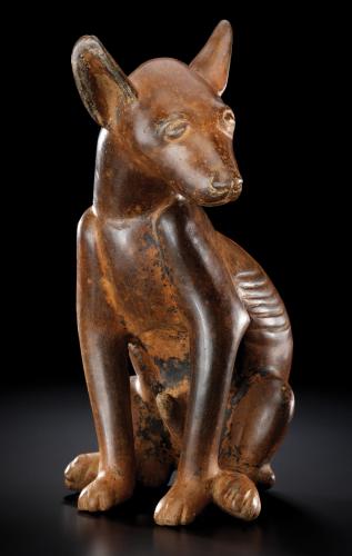 A small brown xolo dog figurine, brightly lit against a black background.