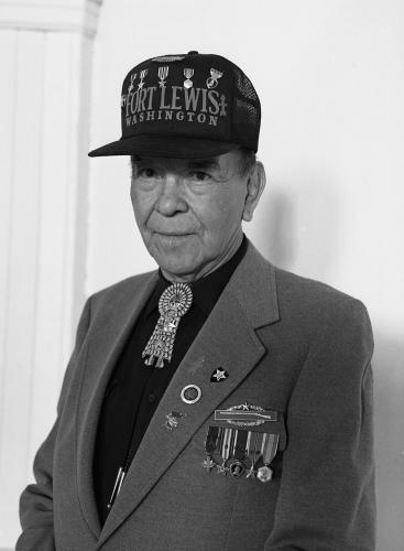 A black and white portrait of a veteran in a suit and various military regalia.