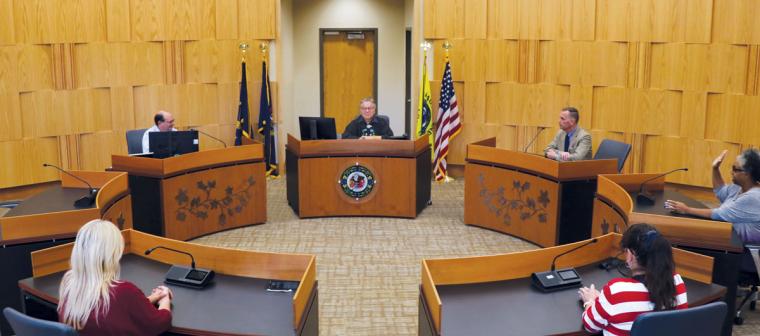 A courtroom with people, including a judge, sitting at tables arranged in a circle