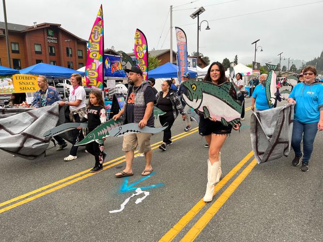 People carry painted props of fish during a pantomime of a Klamath River dam removal