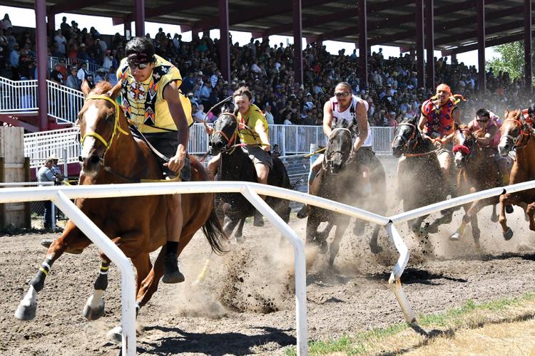 Riders race horses on a track