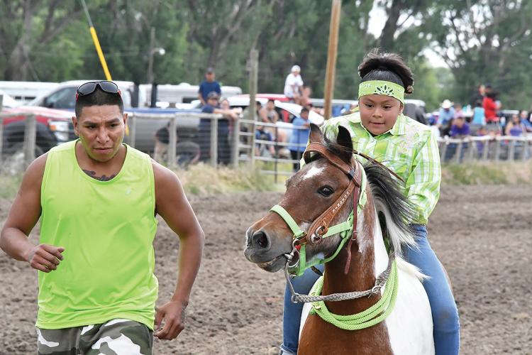 A youth rider races a horse while an adult runs alongside them