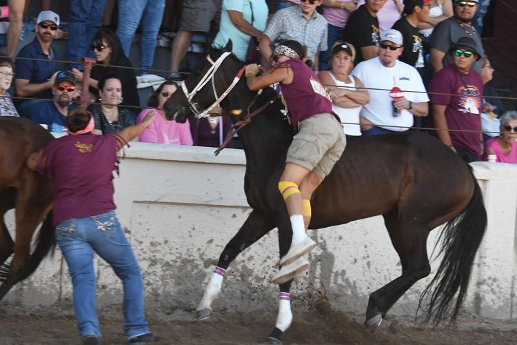 A rider is shown dismounting her racehorse, in front of a crowd