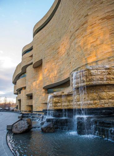 A curving exterior stone wall with a water feature