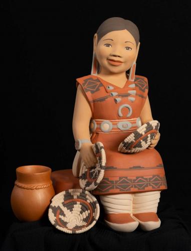 Ceramic sculpture showing woman in red dress with black patterns holding baskets; pot and basket are beside her