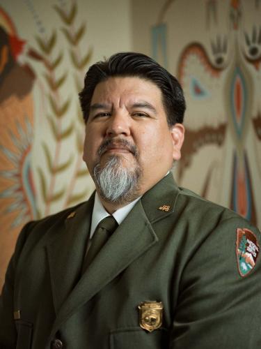 Charles Sams III poses for an official portrait in a green National Park Service uniform.