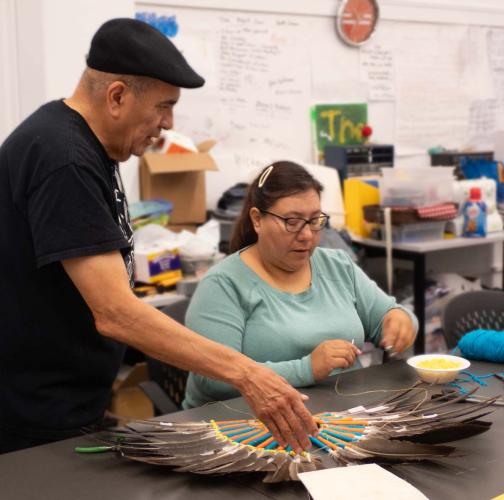Steven Tamayo teaches a woman how to make a bustle out of feathers