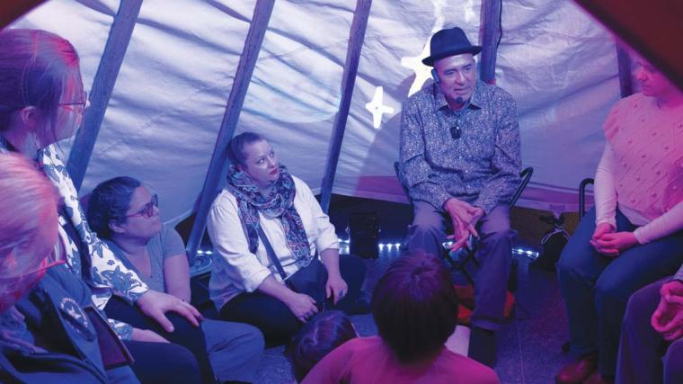 Steven Tamayo tells creation stories with images he created projected behind him on a screen.