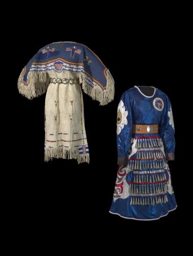 Two dresses stand back to back on mannequins: the dress on the left depicts American flags and stripes made with tanned hide. The dress on the right is constructed with blue fabric and ordained with metallic cones, military patches, and sequins.