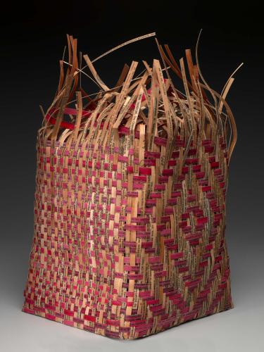 A woven basket of red and brown reeds printed with words. The top edge of the basket remains undone and frayed.