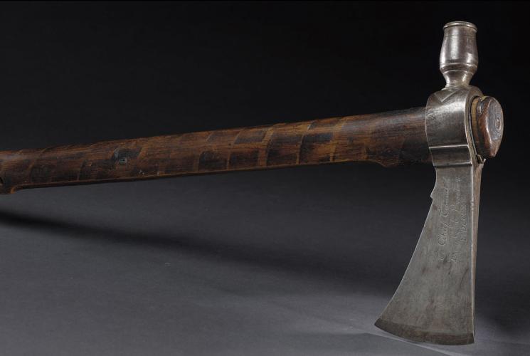 A pipe with a long wooden handle and a sturdy pipe made of iron and lead.