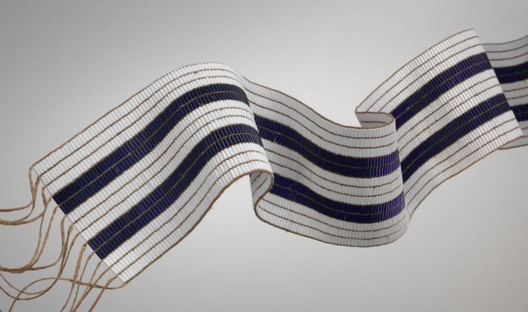 A wide beaded belt with three white and two dark blue stripes.