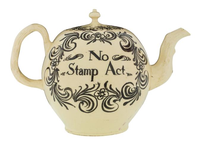 A ceramic teapot embellished with a floral design reading "No Stamp Act."
