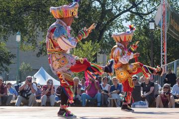Peruvian dancers in colorful costumes perform outdoors in front of an audience