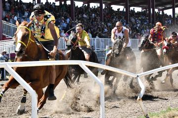 Racehorses and their riders take off at the start of a relay race