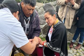 Three people on a stone path crouch over a box holding ancestral remains