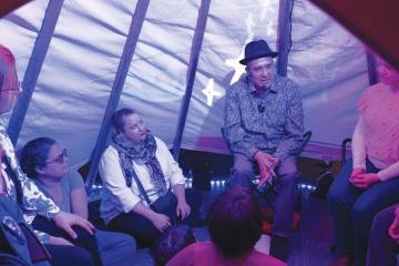 Steven Tamayo tells creation stories with images he created projected behind him on a screen.