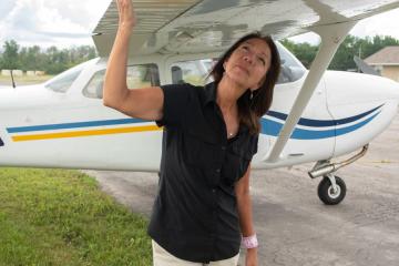 Jo-Anne Tabobandung stands beneath and holds the wing of her airplane.